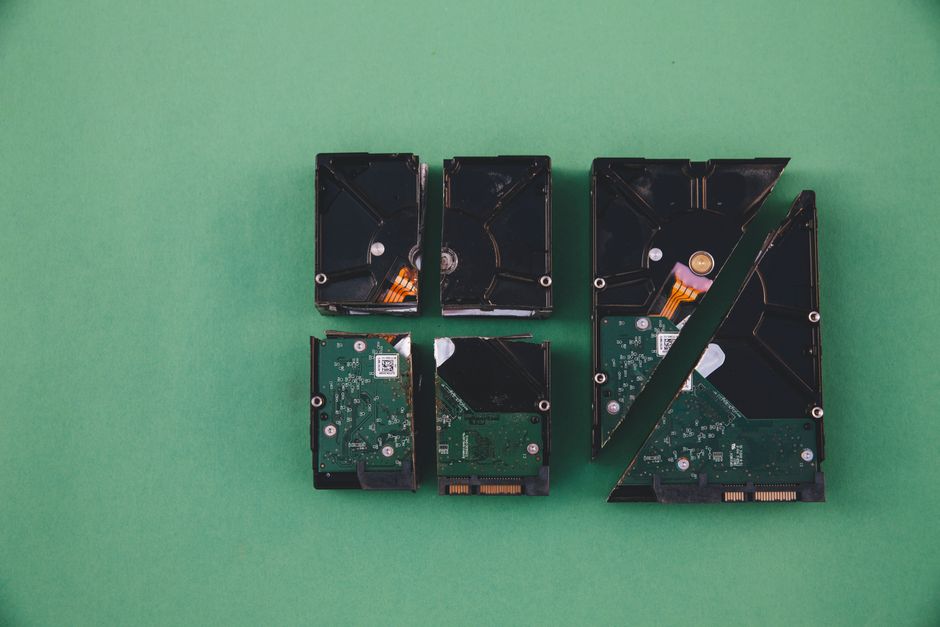 Four broken hard drives arranged on a green background, showcasing data destruction.